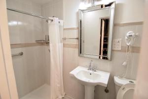 a white bathroom with a shower and a sink at Sheridan Hostel in Dania Beach