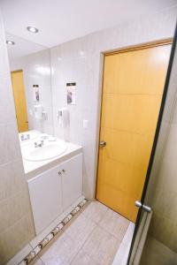 a bathroom with a sink and a yellow door at WinMeier Hotel y Casino in Chiclayo