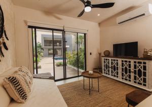 a living room with a couch and a flat screen tv at Kaanal Tulum in Tulum