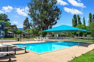 a swimming pool with a blue umbrella and chairs at BIG4 Taggerty Holiday Park in Taggerty