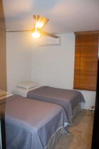 - une chambre avec 2 lits et un ventilateur de plafond dans l'établissement Departamento comodo, a media cuadra de la playa., à Mazatlán