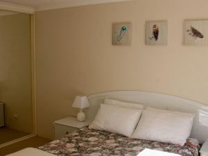 a bedroom with a bed and three pictures on the wall at The Clippers 1 fabulous waterfront unit in Salamander Bay