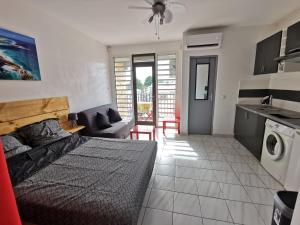 a bedroom with a bed and a kitchen with a washing machine at Appartement vue mer et montagne à 100m de la plage in Le Gosier