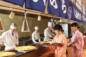 a group of chefs preparing pizzas in a kitchen at Ooedo Onsen Monogatari Hotel Kinugawa Gyoen in Nikko