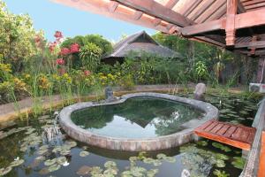 a koi pond with a bench in a garden at Hotel Pondok Sari Beach & SPA Resort in Pemuteran