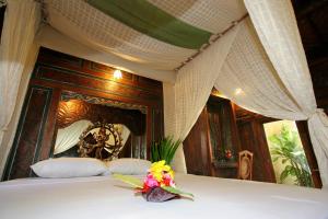 un letto a baldacchino con un fiore sopra di Hotel Pondok Sari Beach & SPA Resort a Pemuteran