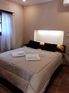 1 dormitorio con 1 cama grande y toallas. en Cabañas Layken en Villa Carlos Paz