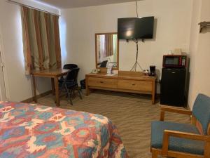 Una habitación de hotel con una cama, un escritorio y un televisor. en Western Motel, en Deming