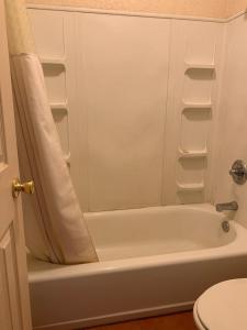 Un baño con bañera blanca y un inodoro. en Western Motel, en Deming