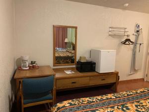 a room with a desk and a mirror and a bed at Western Motel in Deming