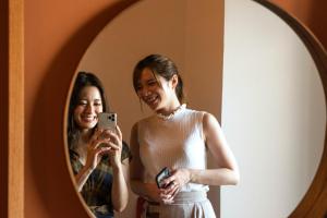 a woman taking a picture of herself in a mirror at EARTHMANS OSAKA-JO in Osaka