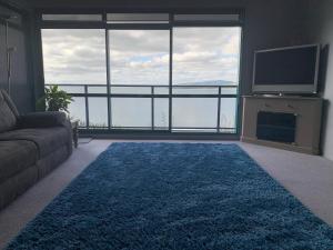 a living room with a couch and a large window at Harbour Lane Apartment in Whangarei