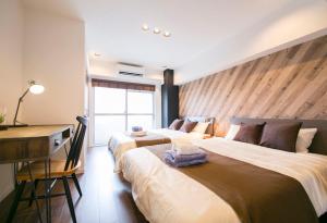 a hotel room with two beds and a desk and a desk at Shibuya Park Residence Yoyogi Park in Tokyo