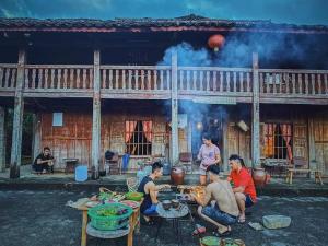 a group of people sitting around a table in front of a building at Lo Lo Homestay & Cafe Meo Vac in Mèo Vạc