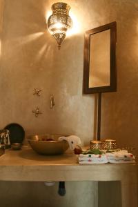 a vanity with a mirror and a bowl on a table at Riad Golfame in Marrakech