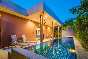 a swimming pool with two chairs and a house at Villa Na Pran, Pool Villa in Pran Buri
