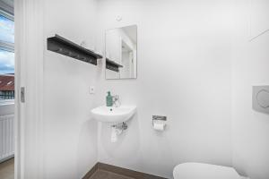 a white bathroom with a sink and a toilet at Kragsbjerggaard in Odense