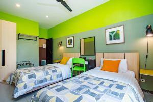 盼武里的住宿－那普蘭泳池別墅，两张床位于带绿色和黄色墙壁的客房