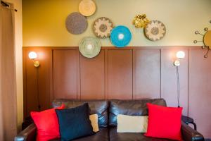 a leather couch with colorful pillows and plates on the wall at Villa Na Pran, Pool Villa in Pran Buri