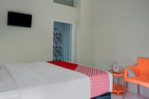 um quarto com uma cama branca e uma cadeira laranja em OYO 3266 Alifah Residence Syariah em Padang