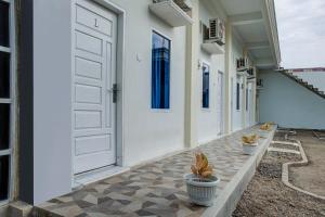 a white door and two potted plants on a patio at OYO 3266 Alifah Residence Syariah in Padang