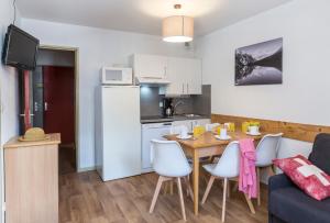 eine Küche und ein Esszimmer mit einem Tisch und Stühlen in der Unterkunft Résidence Odalys L'Ouillon in Saint-Sorlin-dʼArves