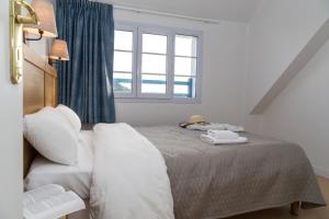 una camera da letto con un letto con lenzuola bianche e una finestra di Résidence Odalys Les Bains a Trégastel