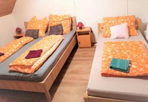 two beds in a room with orange pillows at Barackos Vendégház Bár in Bár