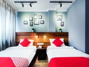 2 bedden in een kamer met rode en witte kussens bij OYO 761 City Hotel in Kuala Lumpur