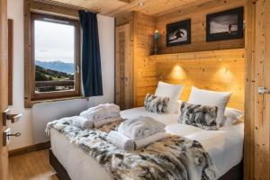 two beds in a room with wooden walls at Whistler Lodge by Alpine Residences in Courchevel