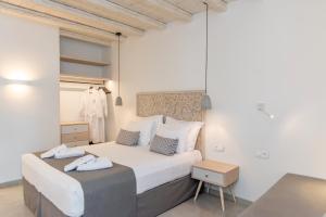 um quarto com uma grande cama branca e uma mesa em Lithos Luxury Suites em Tinos Town
