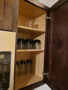 a kitchen cupboard with glass dishes in it at Studio Fort McMurray in Fort McMurray