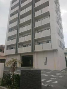 Un grand bâtiment blanc avec un panneau devant. dans l'établissement EX Itoman Apartment 503, à Teruya