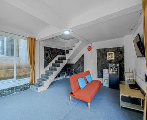 a living room with a red chair and a staircase at DJourney Hotel Lembang by Escotel in Bandung