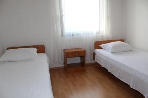 Duas camas num pequeno quarto com uma janela em Apartments Mate em Dolac