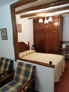 a bedroom with a bed with a mirror and two chairs at hostal ruta de las nieves in Capileira