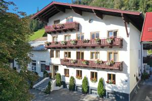 um grande edifício branco com flores nas varandas em Thurners Boutique Hotel em Bruck an der Grossglocknerstrasse