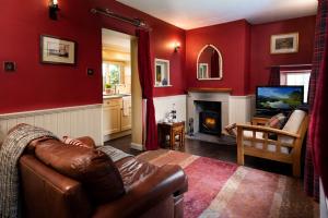 a living room with a leather couch and a television at Gypsy Palace in Kirk Yetholm