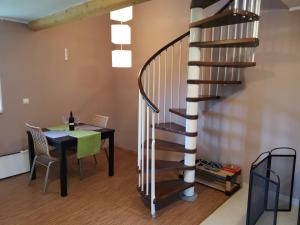 a dining room with a table and a spiral staircase at Vetrovi šumijo II in Kapele