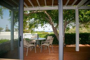 a screened porch with a table and chairs on it at Artemis Village Apartments & Studios in Stavros
