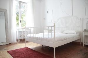 - un lit blanc dans une chambre blanche avec un tapis rouge dans l'établissement Coliving Trastevere, à Rome