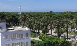 biały dom z palmami i latarnią morską w obiekcie Hotel La Palazzina w mieście San Benedetto del Tronto