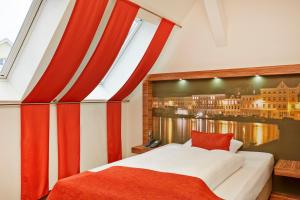a hotel room with a red bed and white curtains at H+ Hotel Lübeck in Lübeck