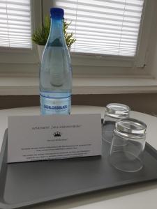 a bottle of water sitting on a tray with two glasses at Apartment Villa Kronenberg in Bochum