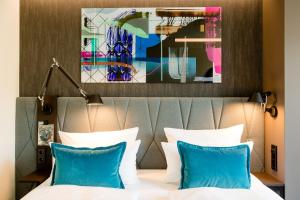 um quarto de hotel com uma cama com almofadas azuis em Motel One Berlin-Hackescher Markt em Berlim