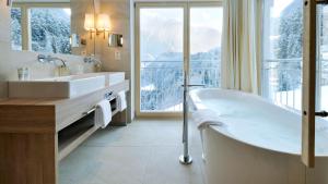 a bathroom with a tub and a large window at Hotel Ritzlerhof - Adults only in Sautens
