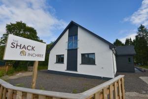 a white house with a sign in front of it at The Shack & Pods at Inchree in Corran