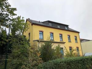 a yellow building with a black roof at Ferienwohnung am Stadtgraben in Wilsdruff