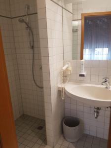 ein Bad mit einem Waschbecken und einer Dusche in der Unterkunft Landgasthof Hotel Grüner Baum in Nürnberg