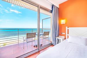 a bedroom with a bed and a balcony with the ocean at Hotel Na Forana in Cala Ratjada